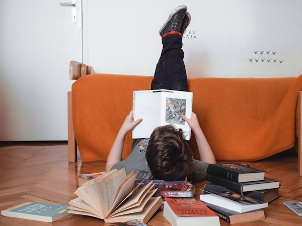 boy reading with feet in the air by Anita Jankovic